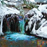 Small waterfall surrounded by snow-covered ground