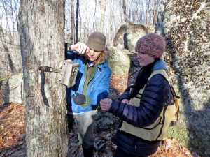 Sally Naser and a volunteer stand by a tree in winter time checking to see if it is set up properly