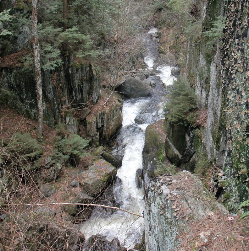 water cascades overs rocks in a river between to rocky cliffs