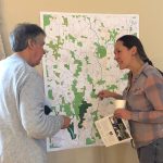 Two people in discussion, in front of a map