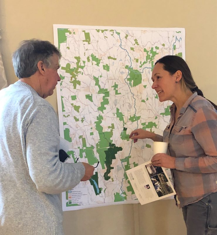 Two people in discussion, in front of a map