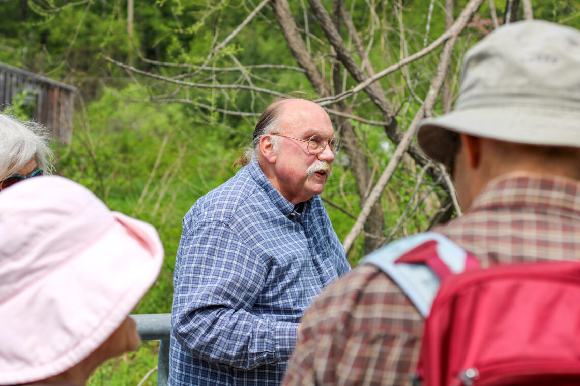 A zoomed-in view of a neighbor, seen through the crowd from the torso up, talking to the group about beavers.