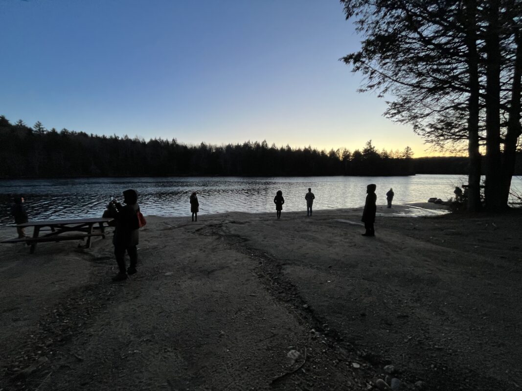 Hikers standing across the Camper's Beach watch the last of the sunset.